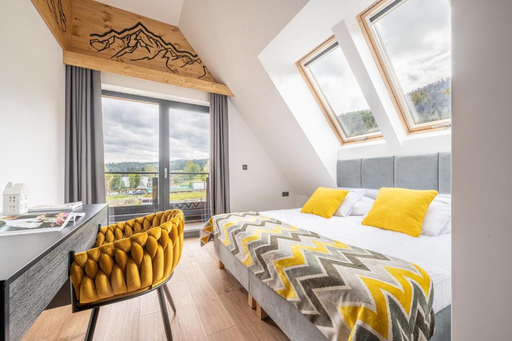 1 dormitorio con cama extragrande y almohadas amarillas en STACJA NOSAL Apartamenty, en Zakopane