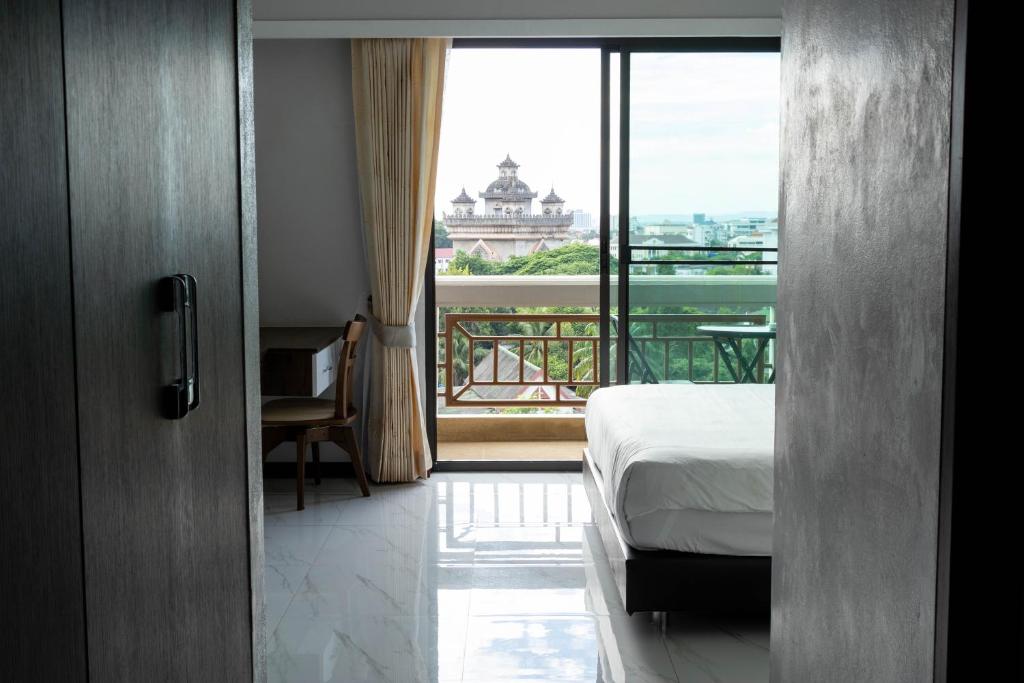 um quarto com uma cama e vista para uma varanda em Urbanite Hotel em Vientiane