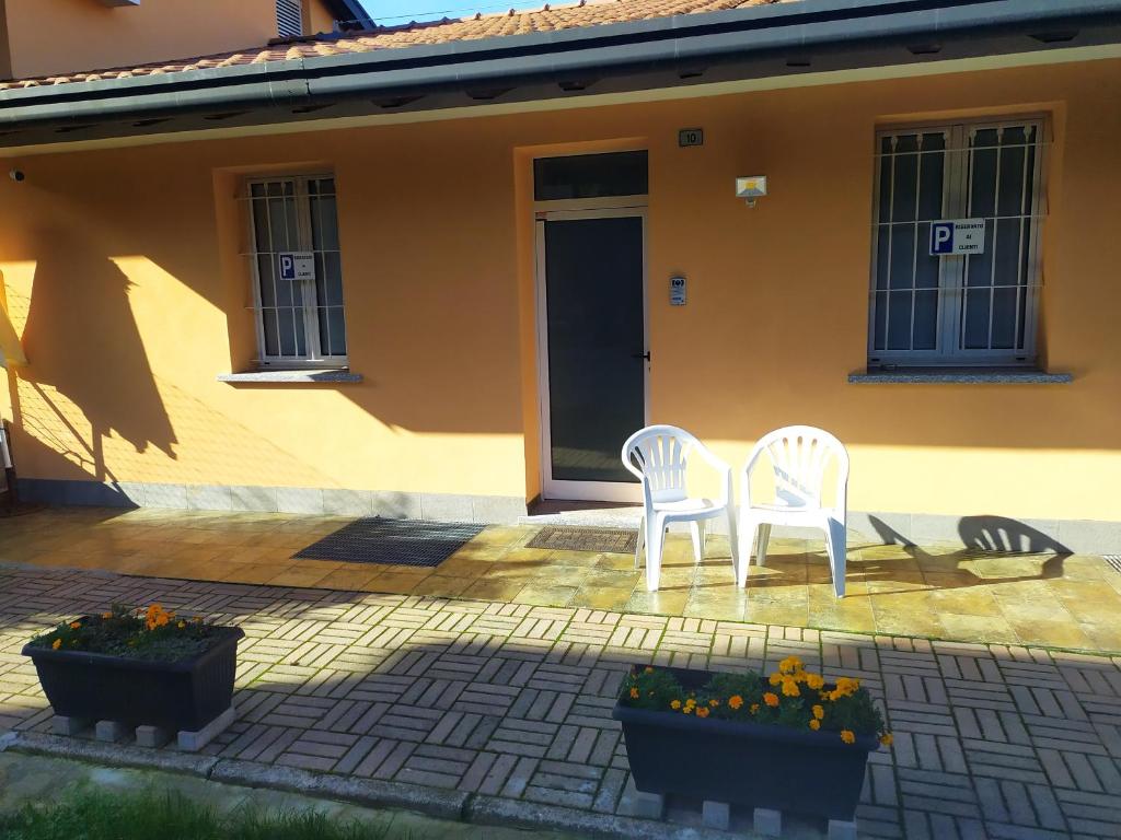 dos sillas blancas sentadas frente a una casa en La Quiete, en Senna Comasco