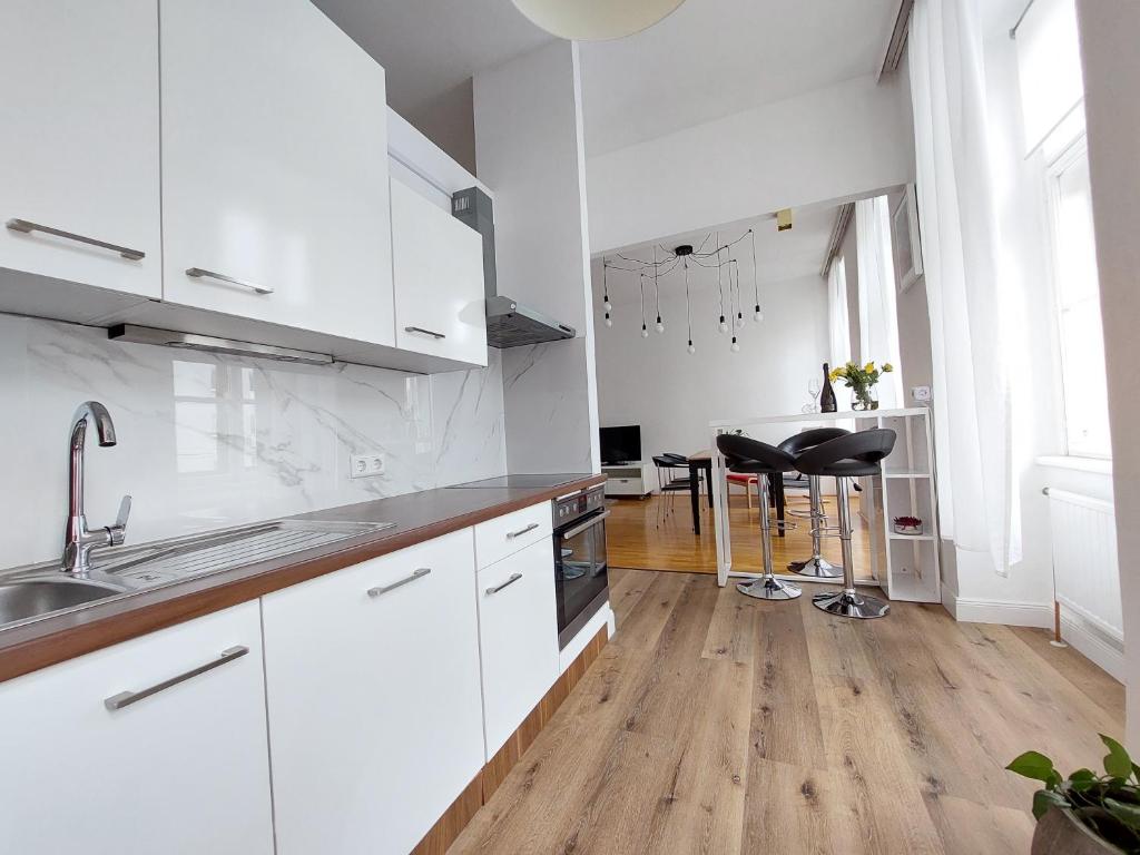 eine Küche mit weißen Schränken und Holzböden in der Unterkunft Vienna Charm Apartment in Wien