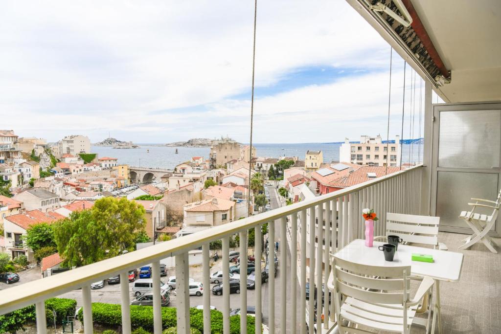a balcony with a table and chairs and a view of a city at Vallon des Auffes - Vue imprenable sur la mer in Marseille