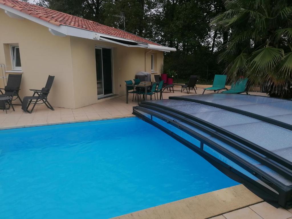 a blue swimming pool with chairs and a house at T2 Tarnos avec piscine in Labenne