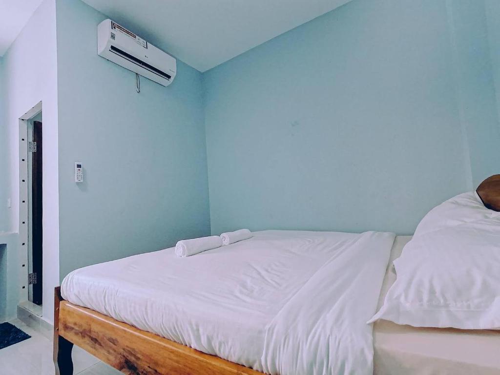 um quarto com uma cama com lençóis brancos e uma ventoinha em Ching Ching Guest House em Sihanoukville