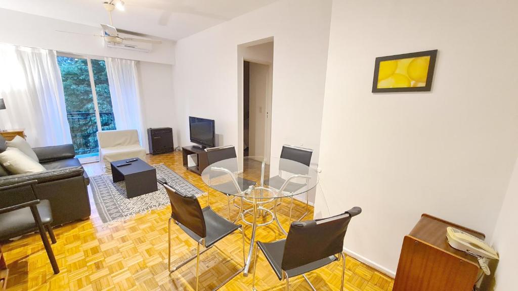 ein Wohnzimmer mit einem Glastisch und Stühlen in der Unterkunft Alquiler temporario en Vicente López in Vicente López