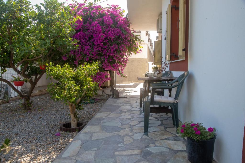a patio with a table and trees and purple flowers at FLOWERS STUDIOS in Skala