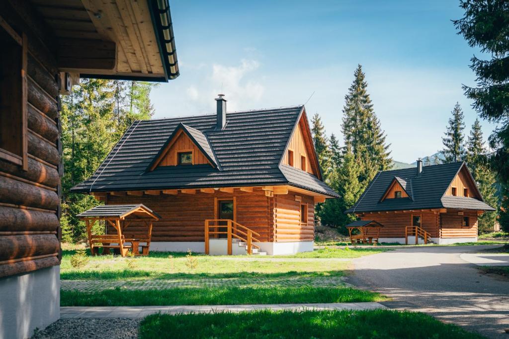 ein großes Holzhaus mit schwarzem Dach in der Unterkunft Rezort pri Jazere Podbanské in Podbanske