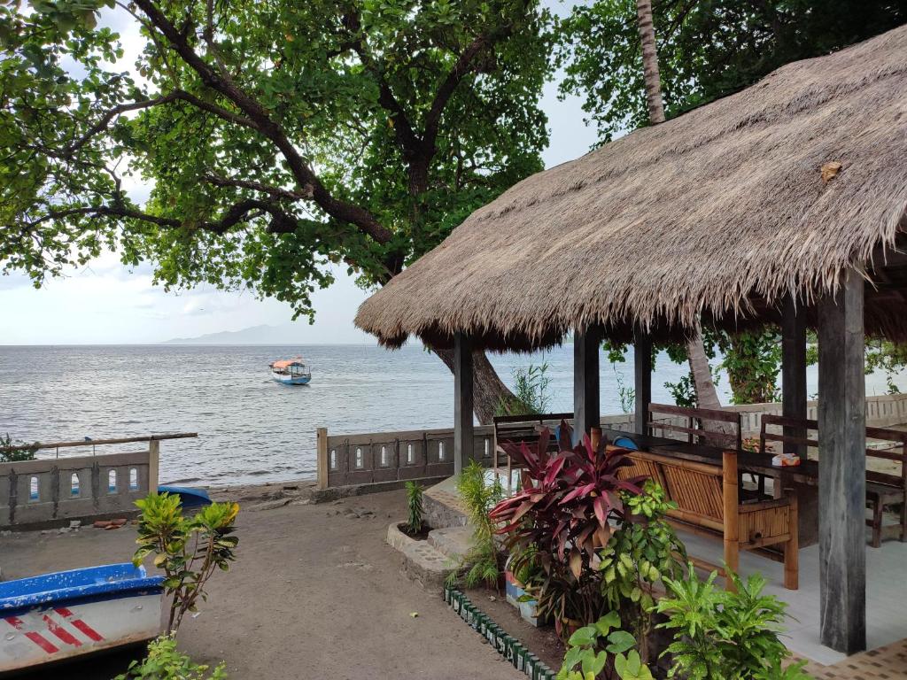 Hitokalak的住宿－Lena house Flores，水中带长凳和船只的小屋