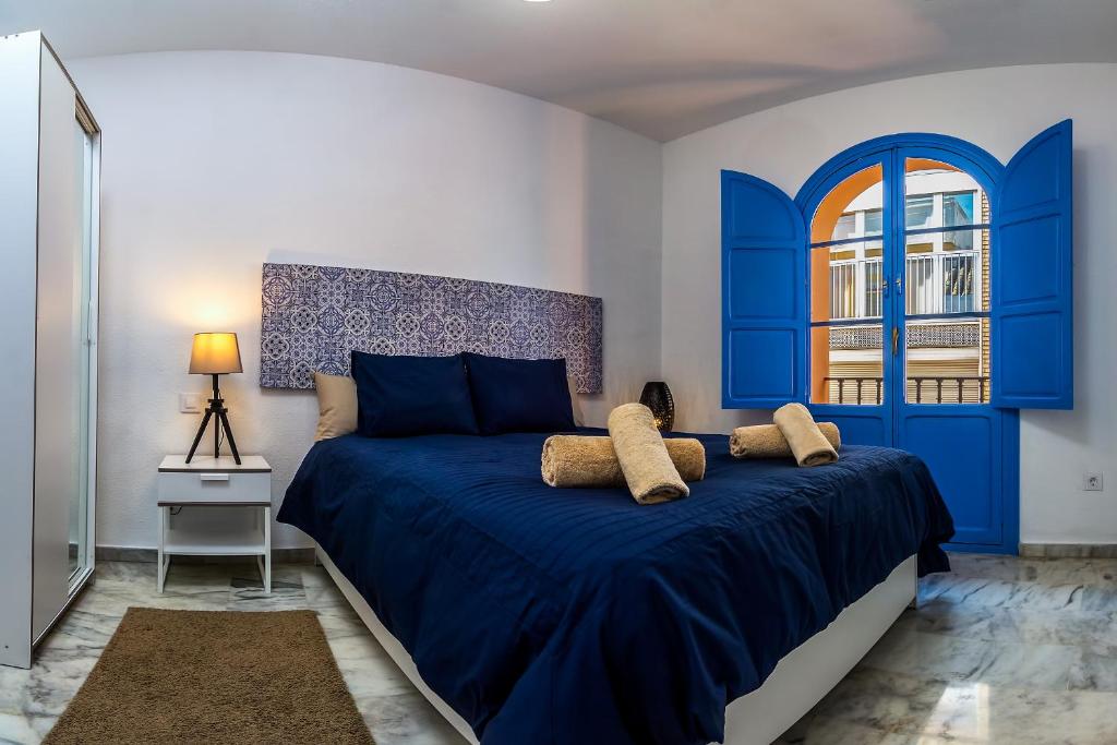 a bedroom with a blue bed and a window at More Center Apartment in Seville