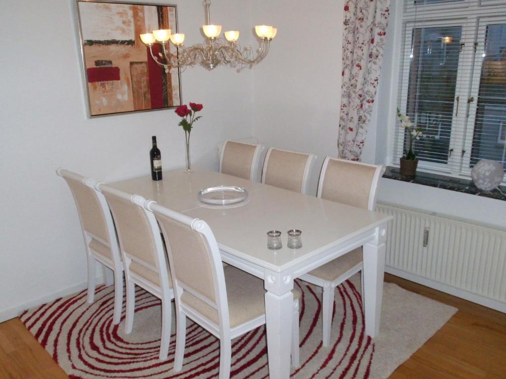 a white dining room table with white chairs and a bottle of wine at Herning City Apartments in Herning