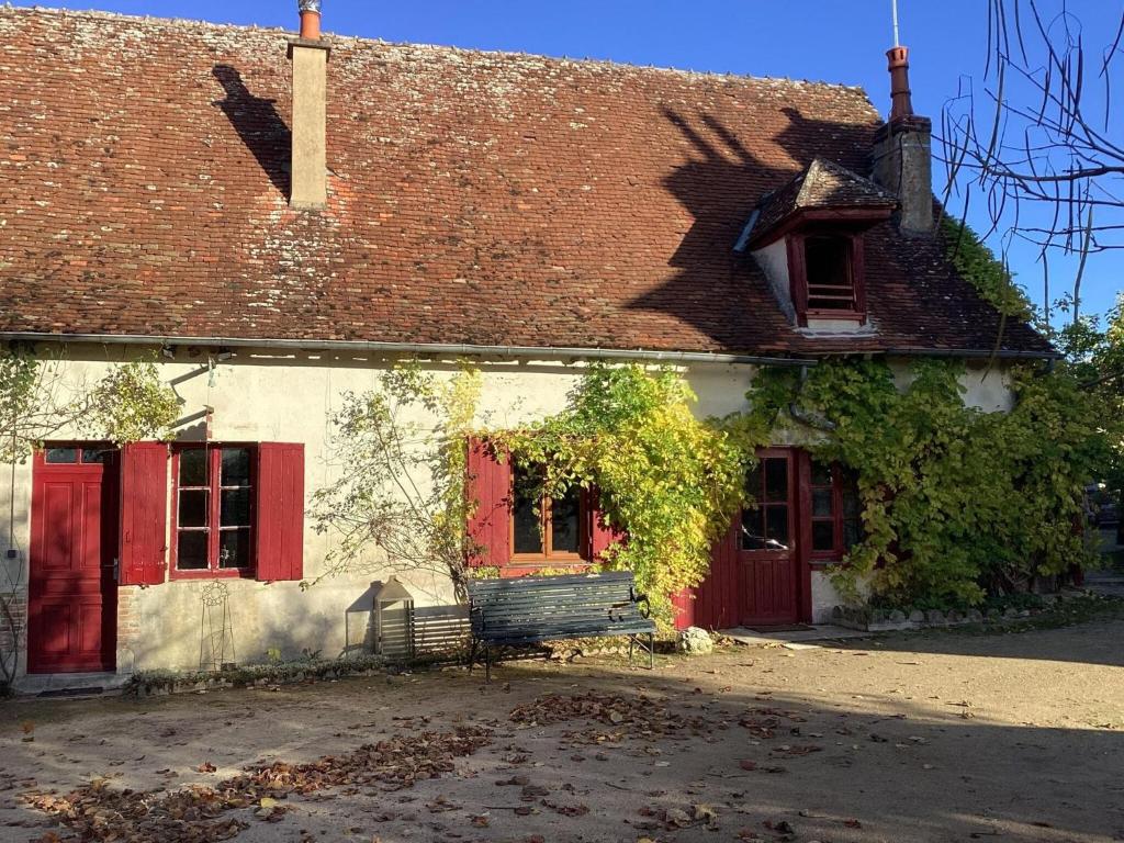 ein weißes Gebäude mit roten Türen und einem roten Fenster in der Unterkunft Pleasant cottage in Le Veurdre with private garden in Le Veurdre