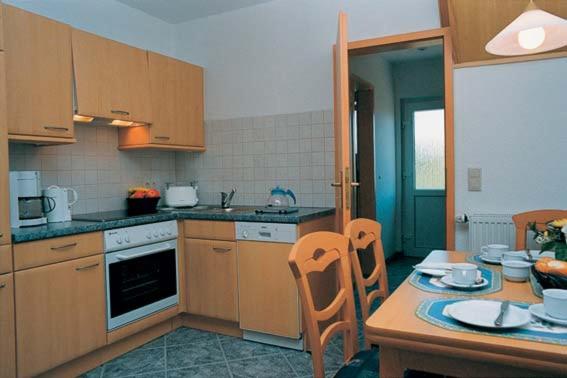 a kitchen with wooden cabinets and a table and chairs at Dünenwind Dünenwind 04 in Norderney