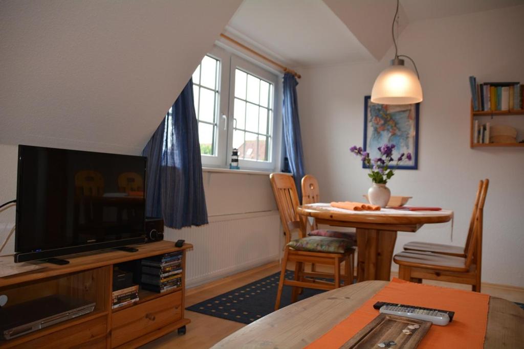 a living room with a television and a dining room table at Up Süderdün 7 Up Süderdün 7 in Norderney