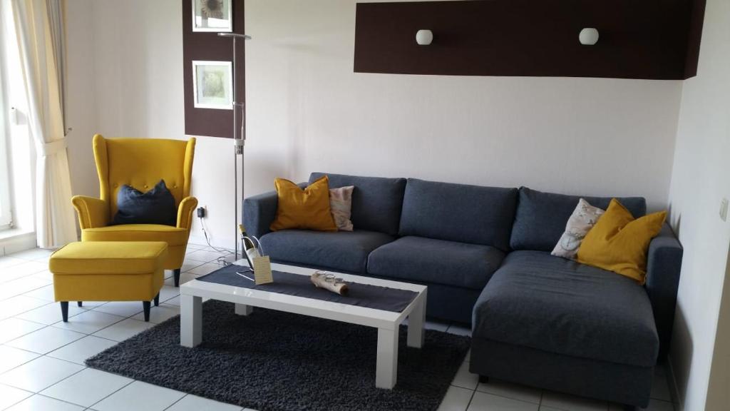 ein Wohnzimmer mit einem blauen Sofa und einem gelben Stuhl in der Unterkunft Residenz am Deich NDD 12 in Norden