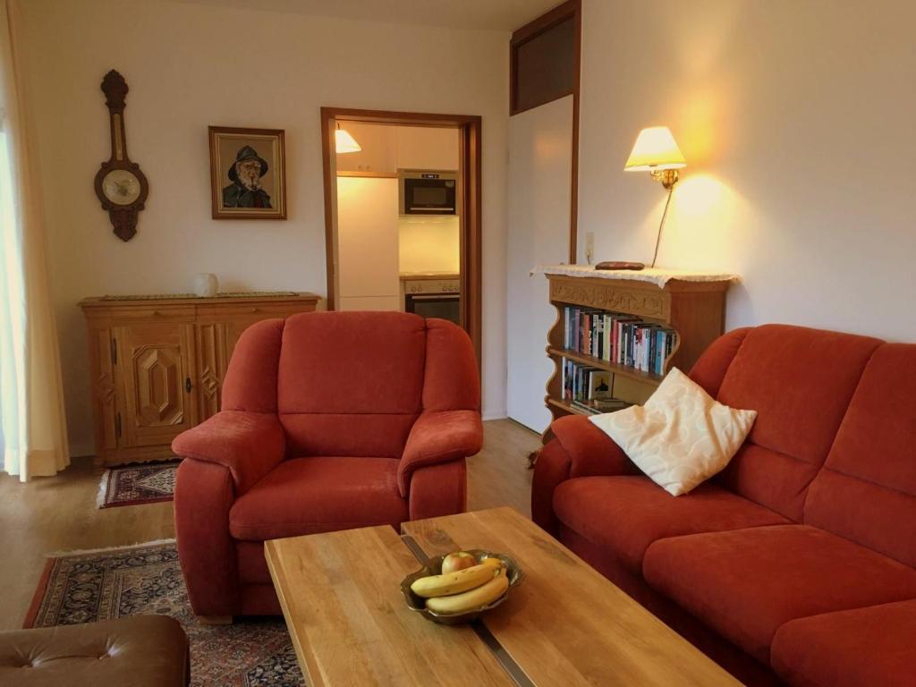 een woonkamer met 2 rode stoelen en een salontafel bij Reichsadler 11 in Norderney