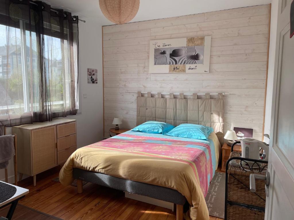 una camera con un letto in una stanza con pavimenti in legno di Manurêva - Chambre d'hôte en coeur de ville a Dinan