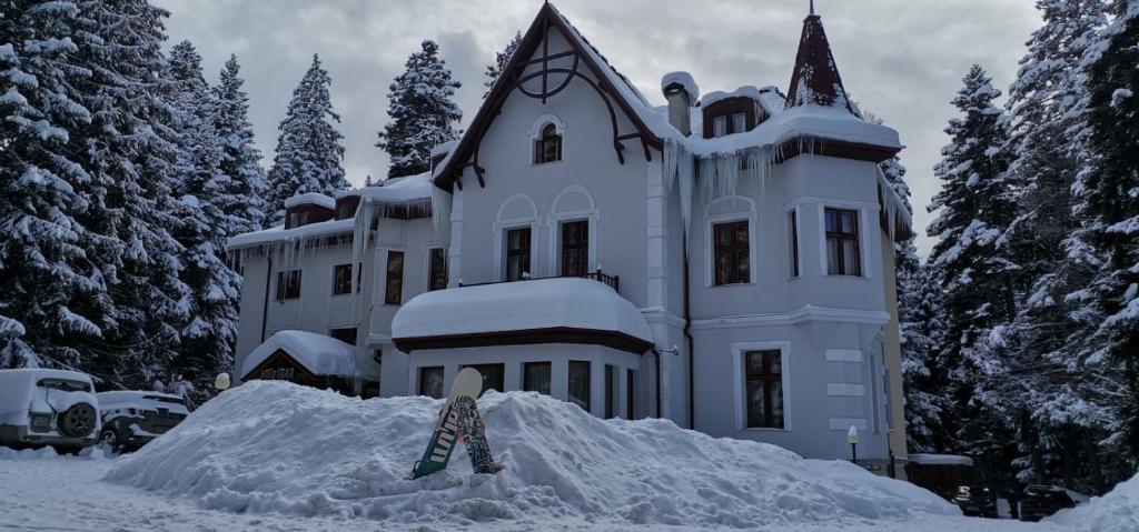 a snowboard in front of a house covered in snow at Villa Ibar in Borovets