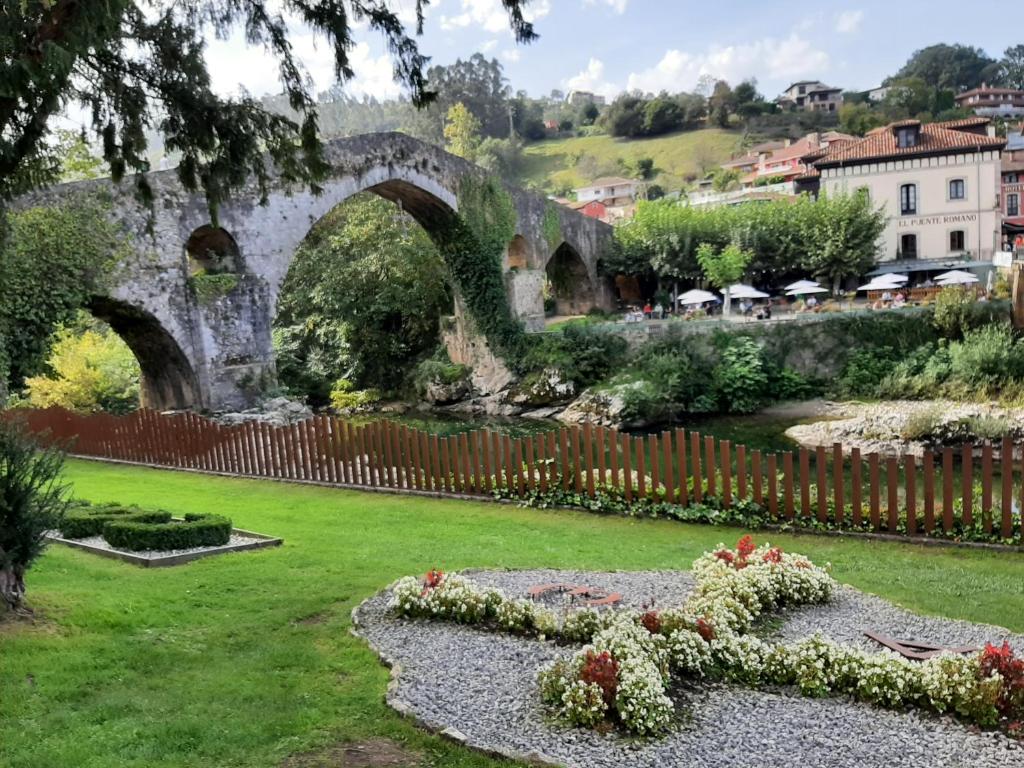 an old stone bridge over a river in a garden at La Playina in Cangas de Onís