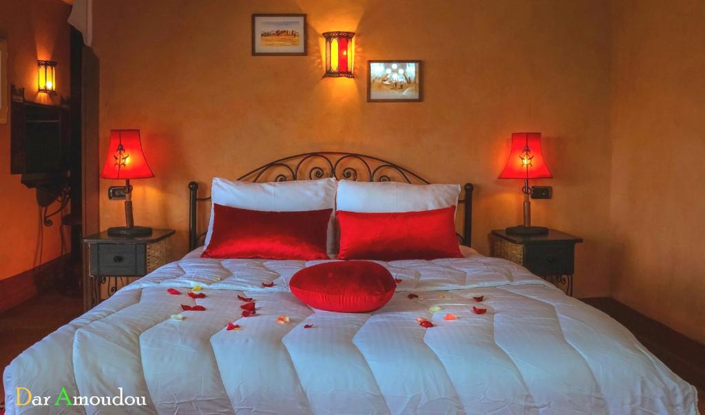 a bedroom with a bed with red pillows and two lamps at Dar Amoudou in Ouarzazate