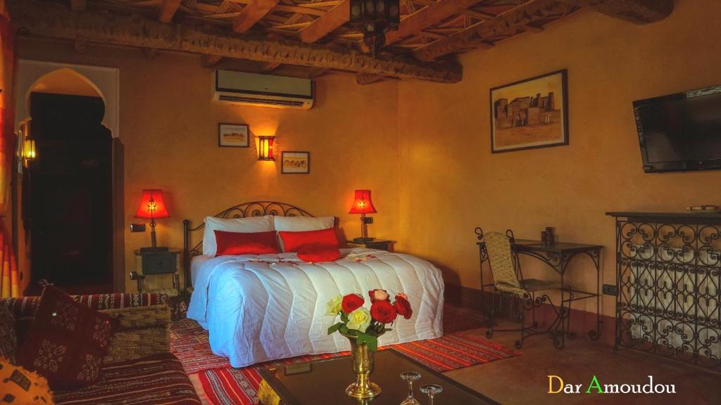 a bedroom with a bed and a vase of flowers on a table at Dar Amoudou in Ouarzazate