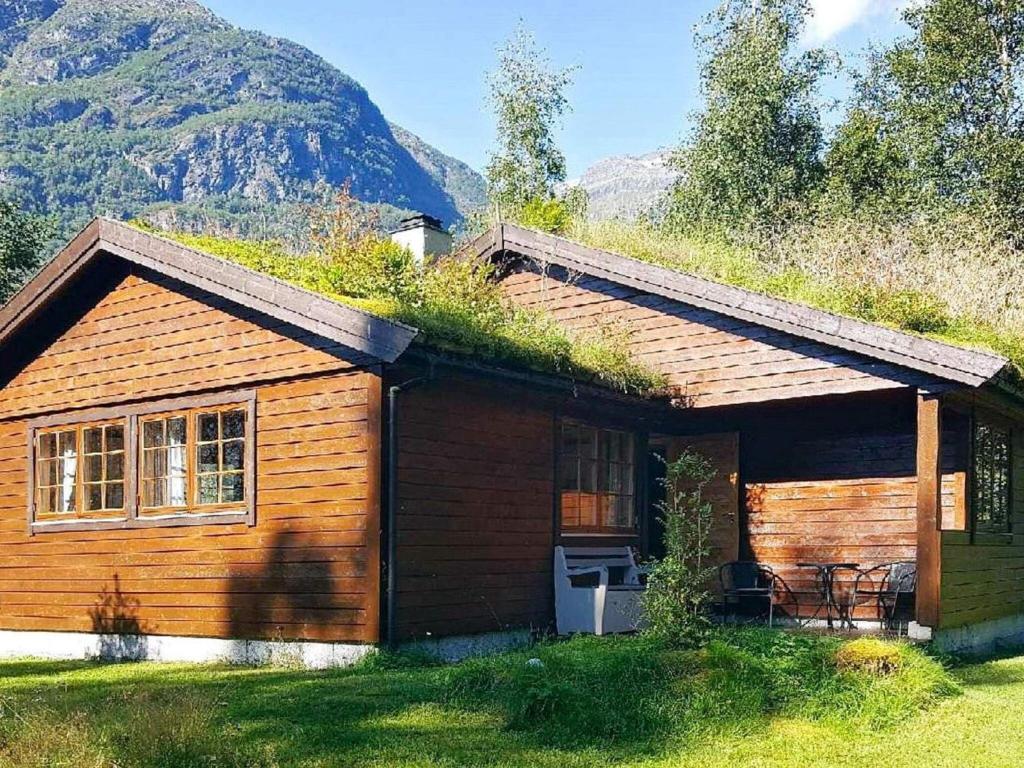 uma cabana de madeira com um telhado de relva e uma casa em Holiday home Oldedalen em Briksdalsbre