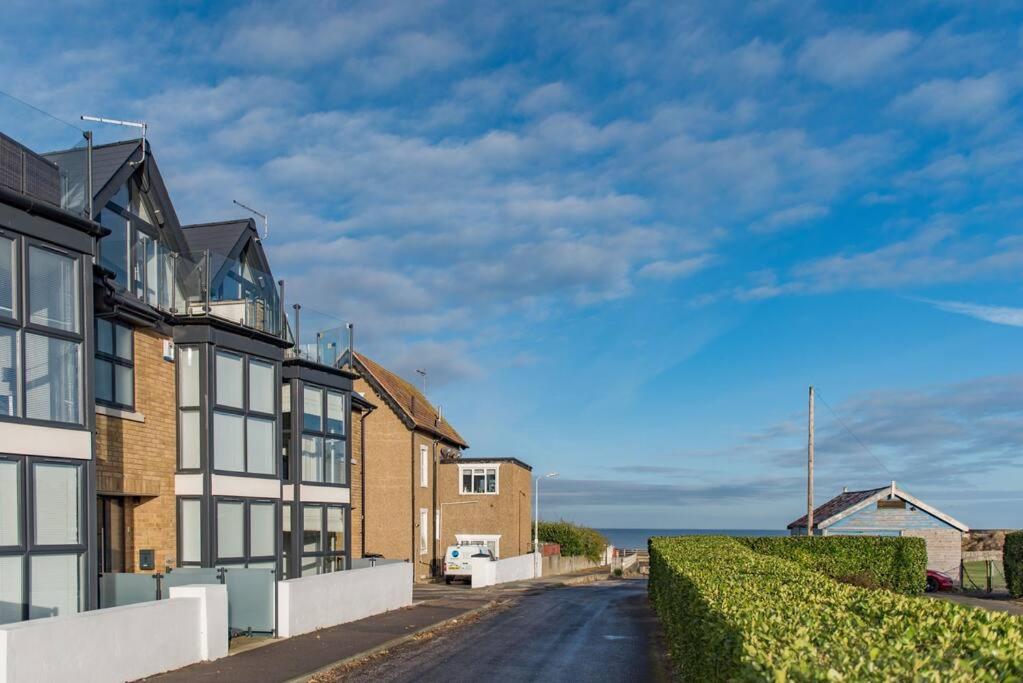 una calle con casas y el océano en el fondo en Sandy Villa en Westgate on Sea