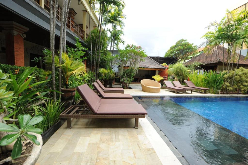 a resort with a swimming pool and lounge chairs next to a building at Tori Inn in Sanur