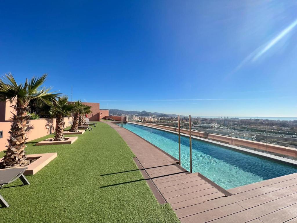 una piscina en la parte superior de un edificio con palmeras en Sky Garden & seasonal pool views by ELE Apartments, en Málaga