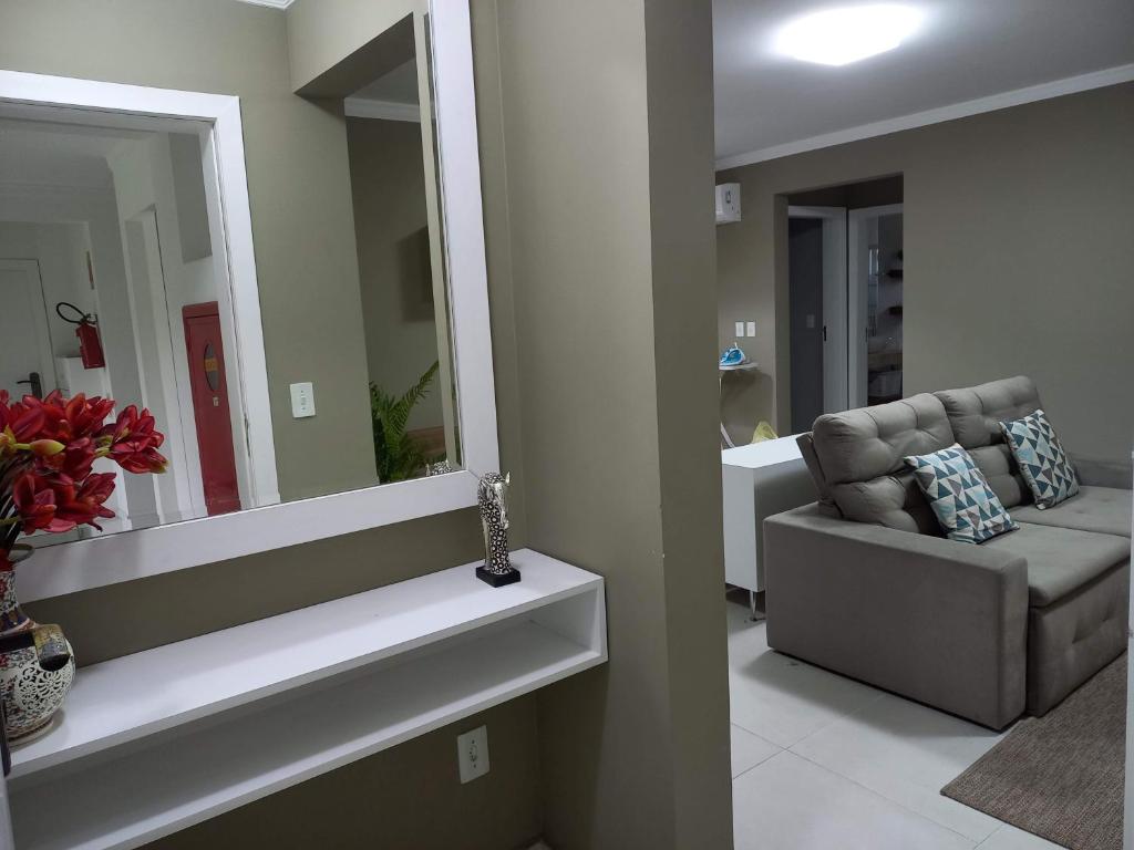 a living room with a chair and a mirror at Apartamento familiar no Centro de Pomerode. in Pomerode