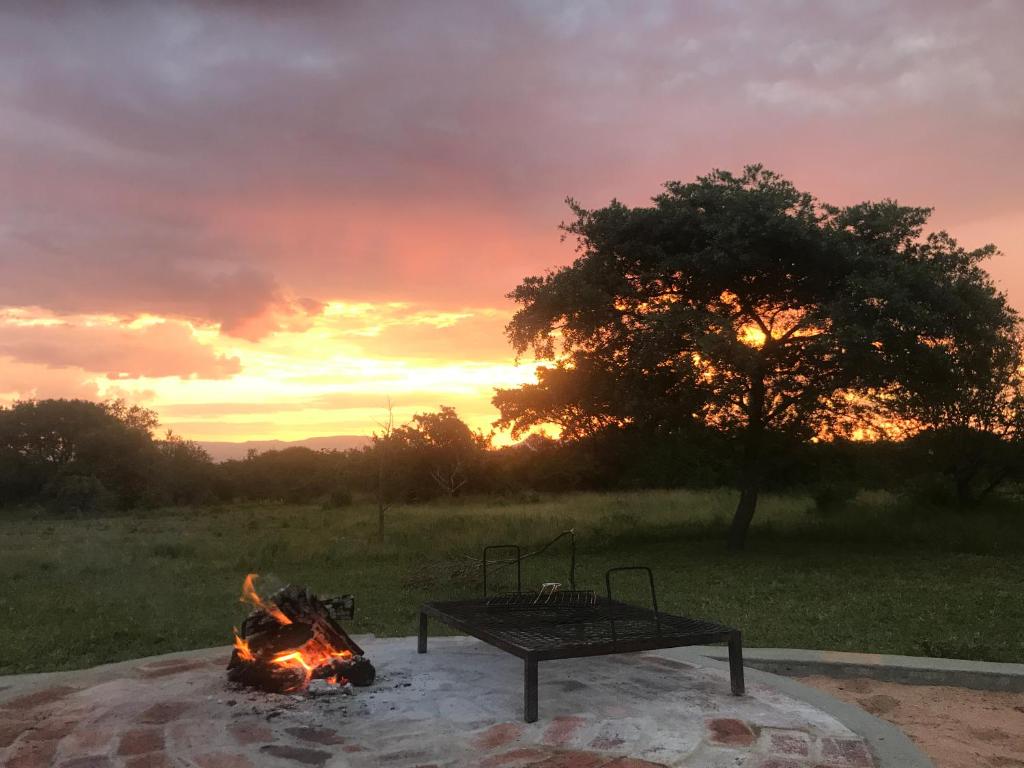 a fire pit with a table and a camp fire at Sunset Lodge & Safaris in Guernsey Nature Reserve