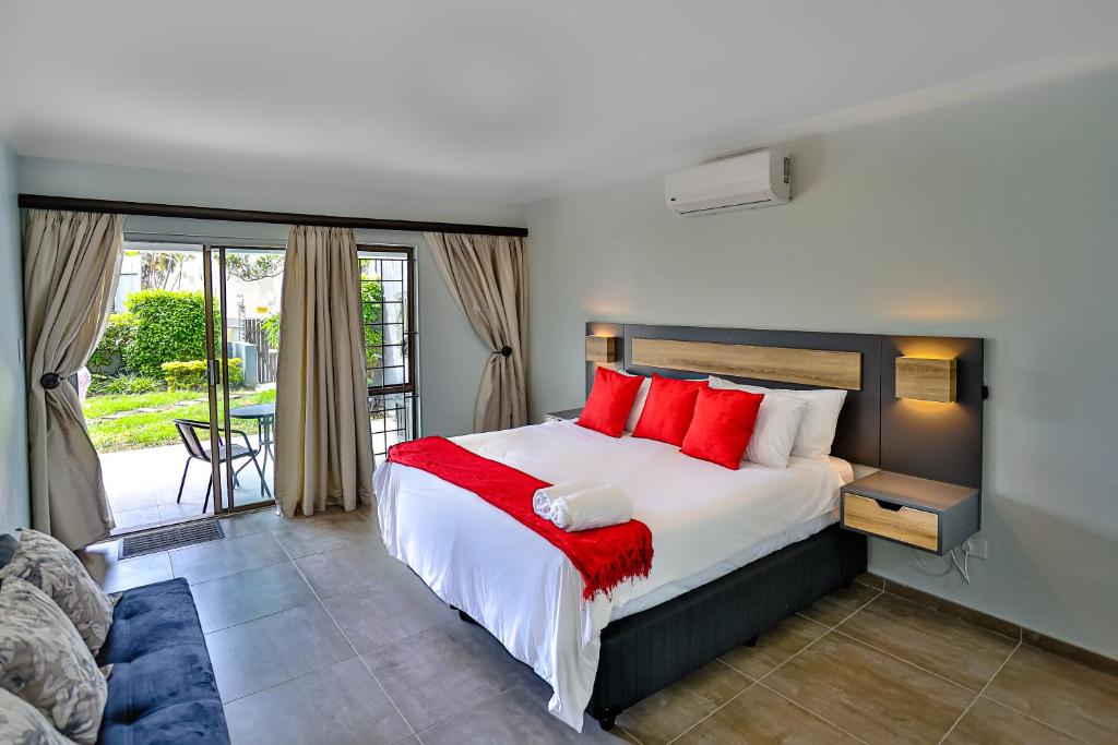 1 dormitorio con 1 cama grande con almohadas rojas en JMK at 49 LaPirogue - Families only, en Ballito