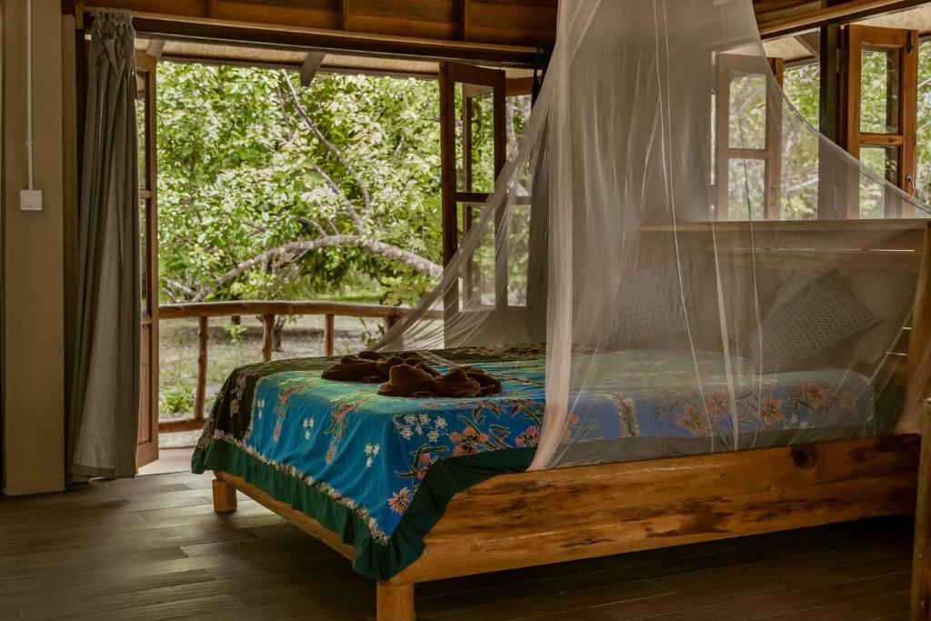 a bed with a canopy in a room with a window at Monkey Mansion - Jungalows & Tours in Khao Sok National Park