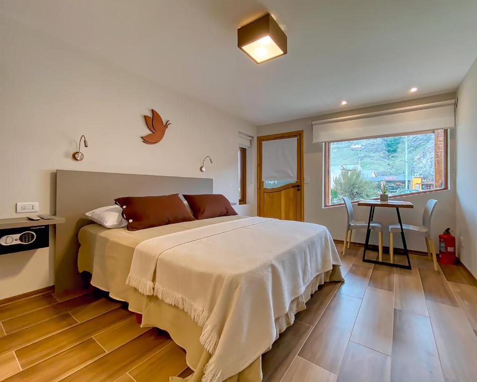 1 dormitorio con cama, mesa y ventana en APARTS LA FARFALLA en El Chaltén