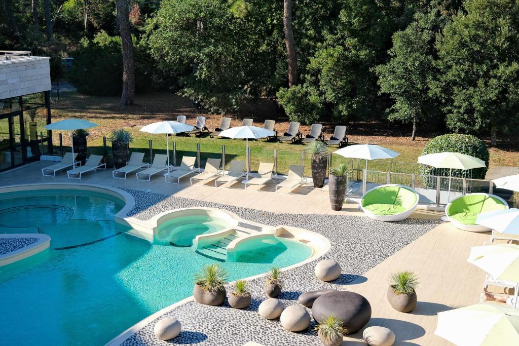 una piscina con sillas y sombrillas junto a un complejo en Thalazur Arcachon - Hôtel & Spa, en Arcachon