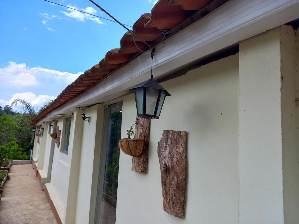 a light on the side of a building with a plant in a basket at Pousada Recanto Alegre in Campestre