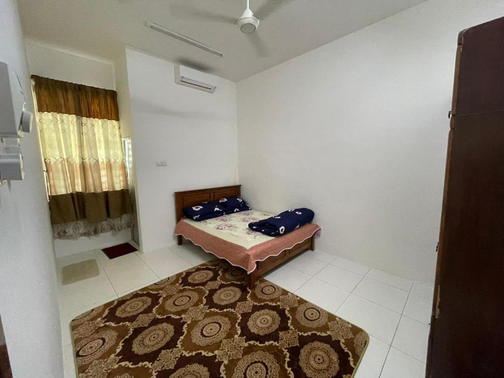 Habitación pequeña con cama y alfombra. en Family Holiday Home With Wifi & Netflix en Sungai Petani