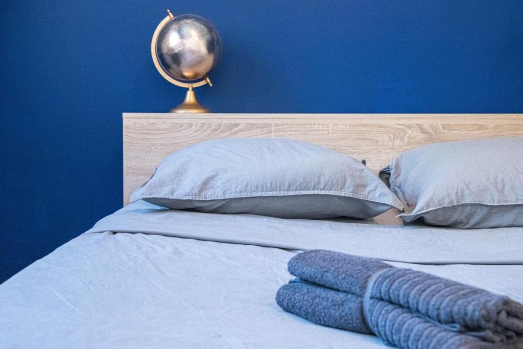 a bed with two pillows and a blue wall at L&#39;Escale - 2 Chambres balcon à 5 min des plages in Marseille