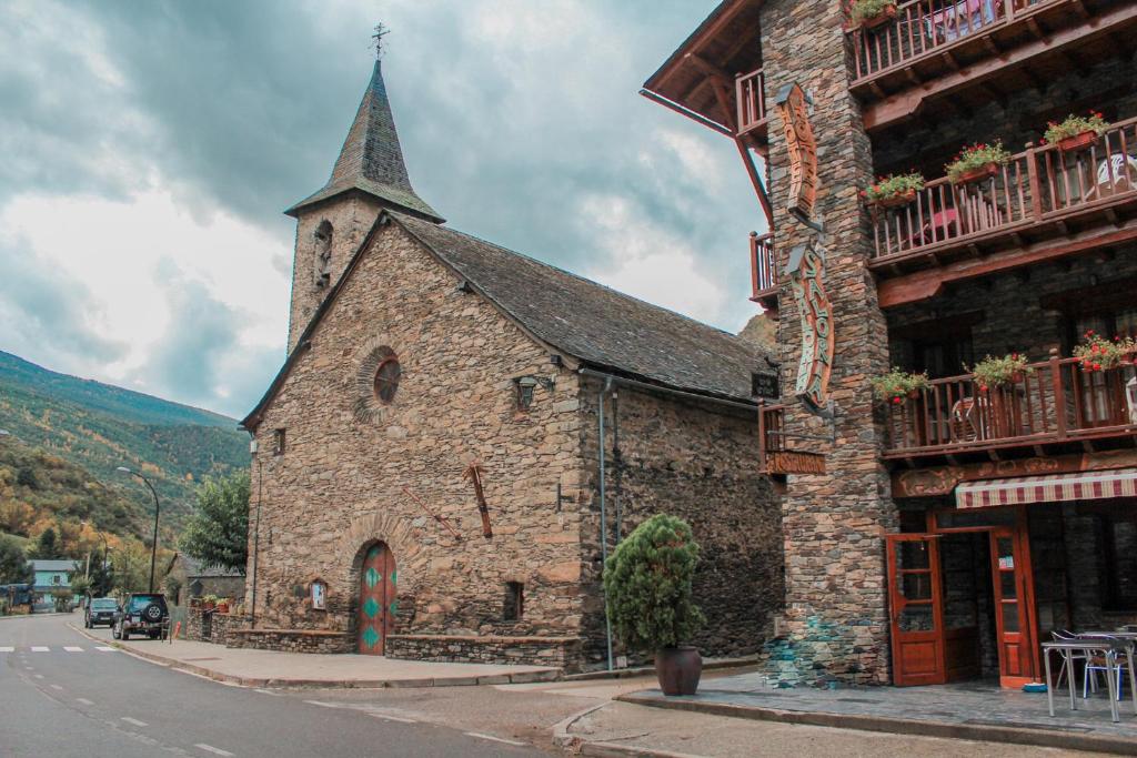 Una vieja iglesia de piedra con un campanario en una calle en Hotel Saloria en Alins
