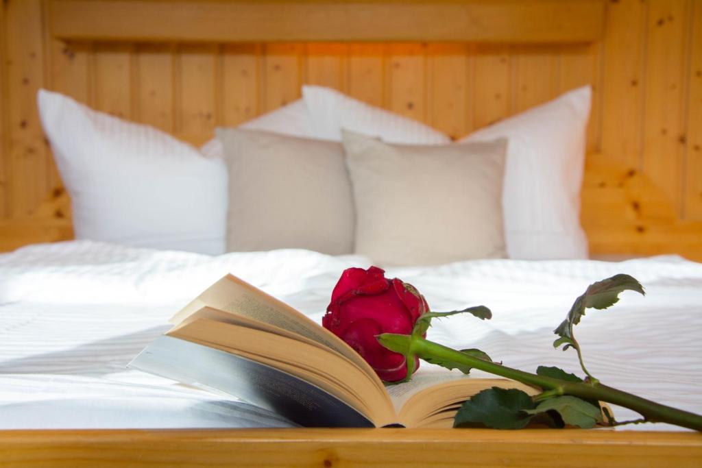 ein Buch und eine Rose auf einem Bett in der Unterkunft Ferienhaus Mühlstein in Silbertal