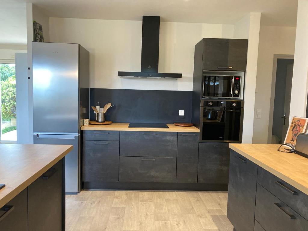 a kitchen with black cabinets and a black refrigerator at Gîte "le haut des Poujades" in Reilhaguet