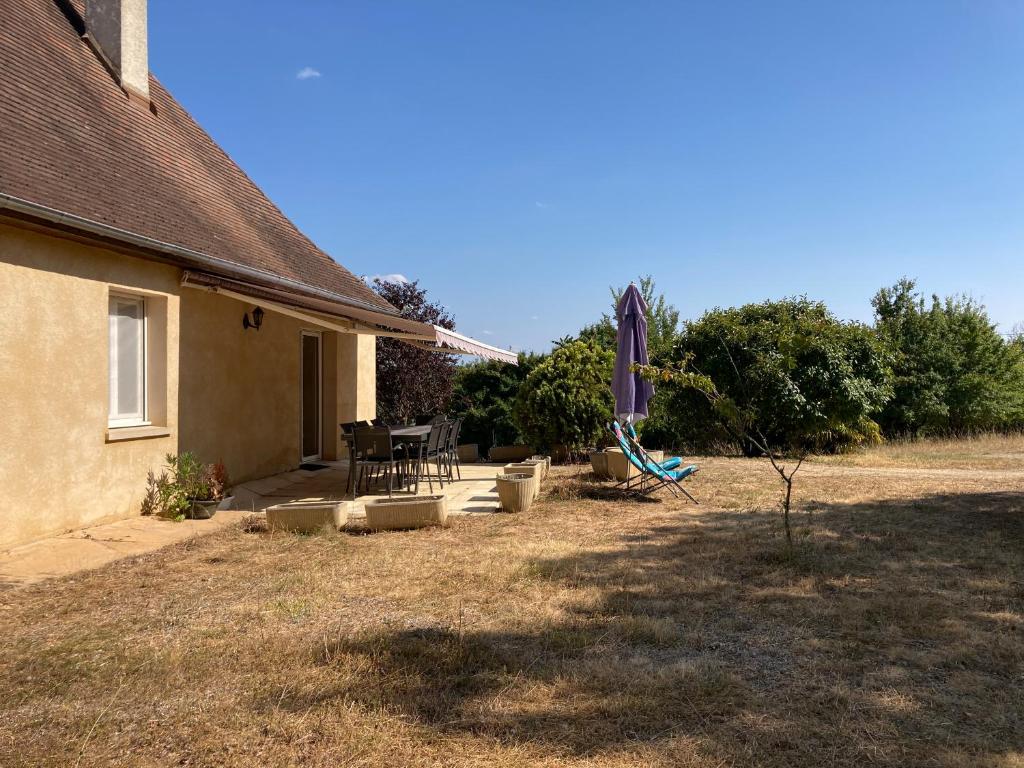 a backyard with an umbrella and a table and chairs at Gîte "le haut des Poujades" in Reilhaguet