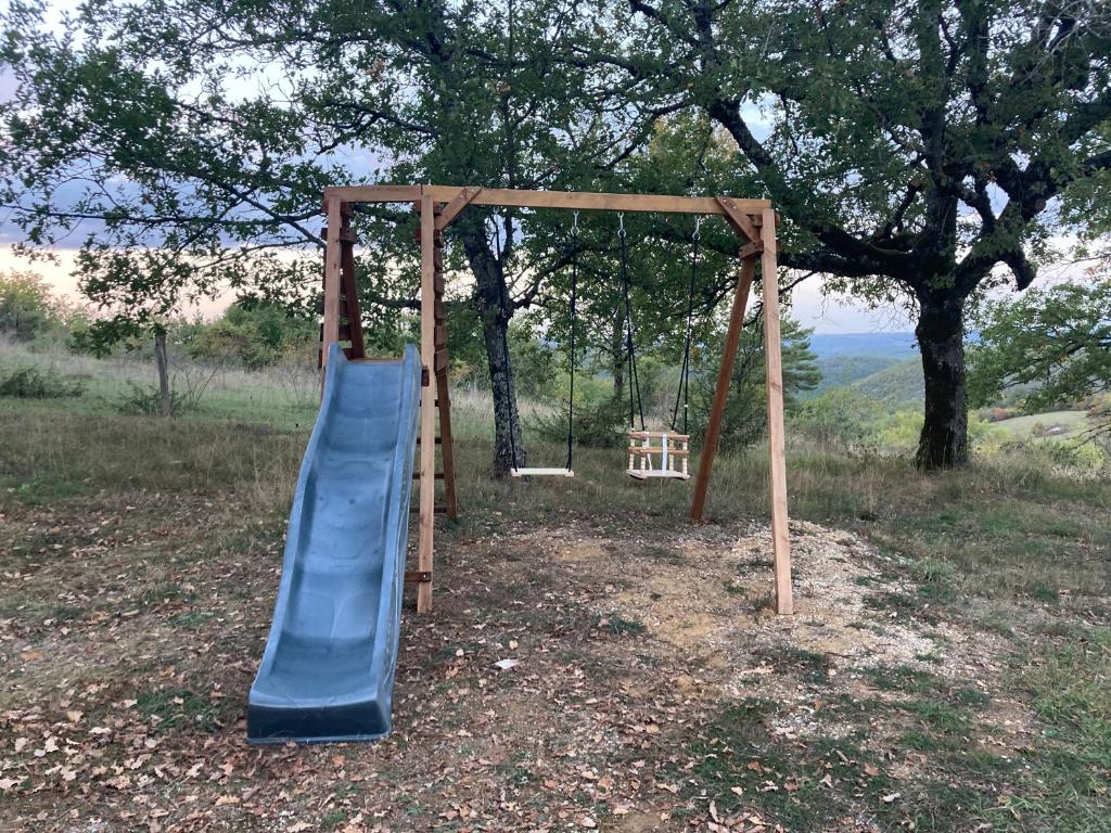 a playground with a slide and a swing at Gîte "le haut des Poujades" in Reilhaguet