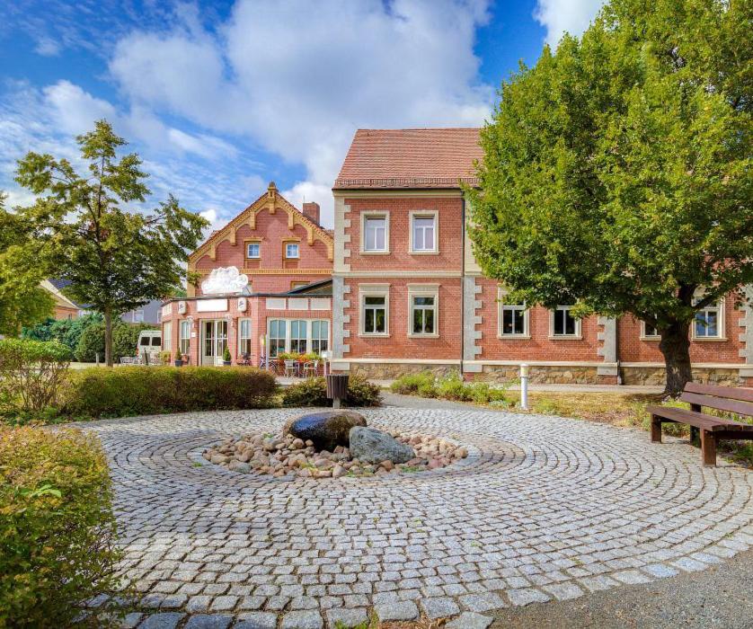 un grand bâtiment en briques avec un arbre et un banc dans l'établissement Hotel Zur Linde, 