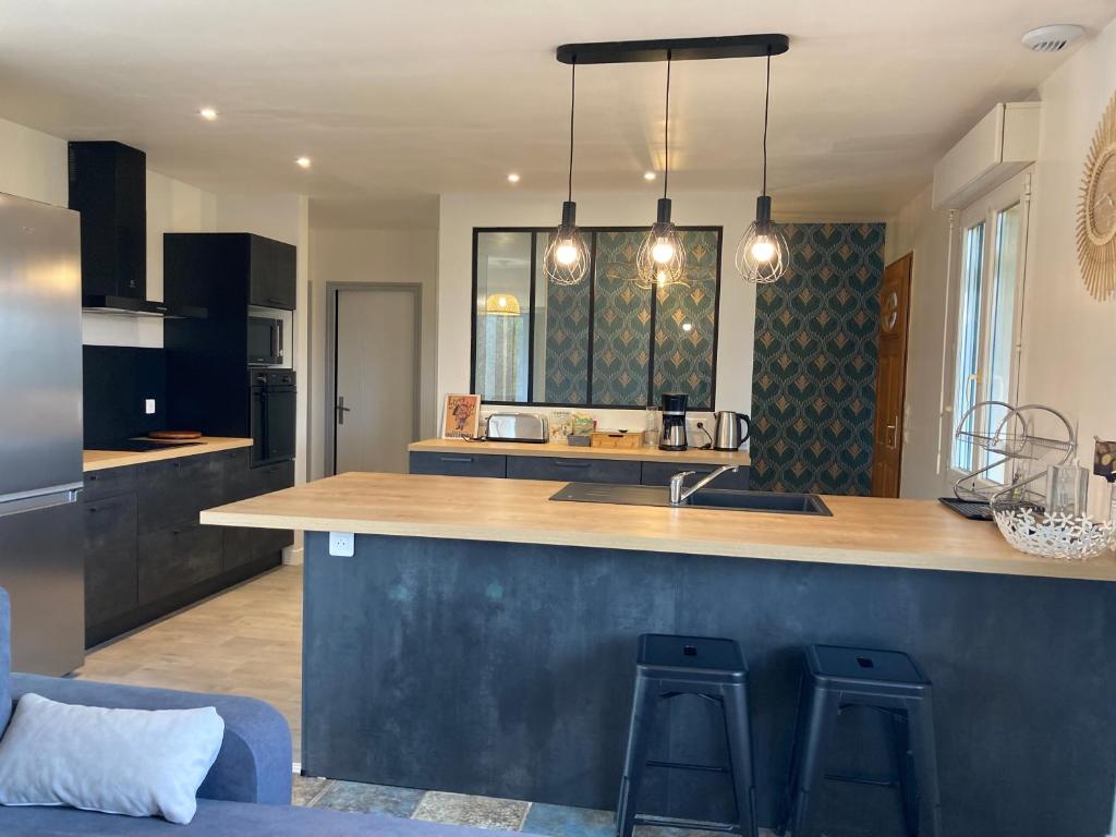 a kitchen with a counter and two bar stools at Gîte "le haut des Poujades" in Reilhaguet