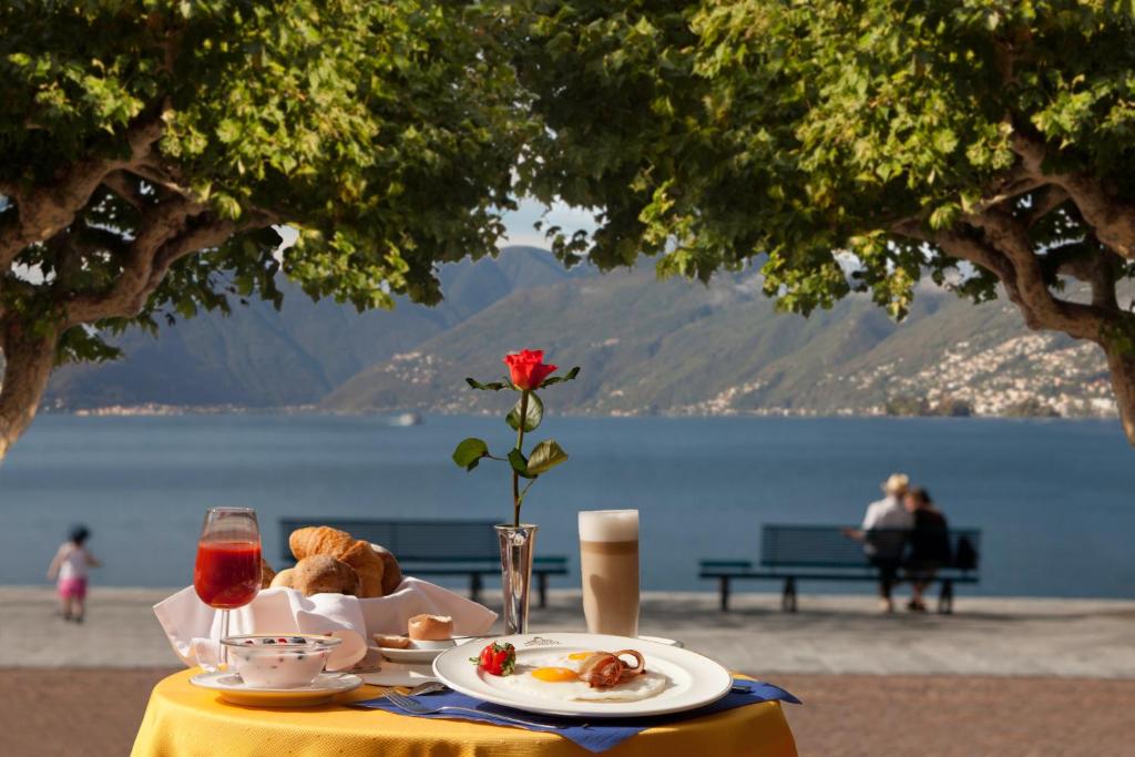 a table with a plate of food with a view of the water at Hotel Tamaro in Ascona