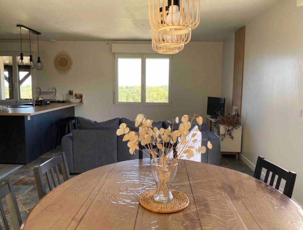 a dining room table with a vase of flowers on it at Gîte "le haut des Poujades" in Reilhaguet