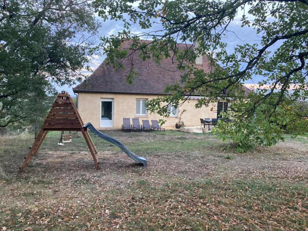 a wooden swing set in front of a house at Gîte "le haut des Poujades" in Reilhaguet