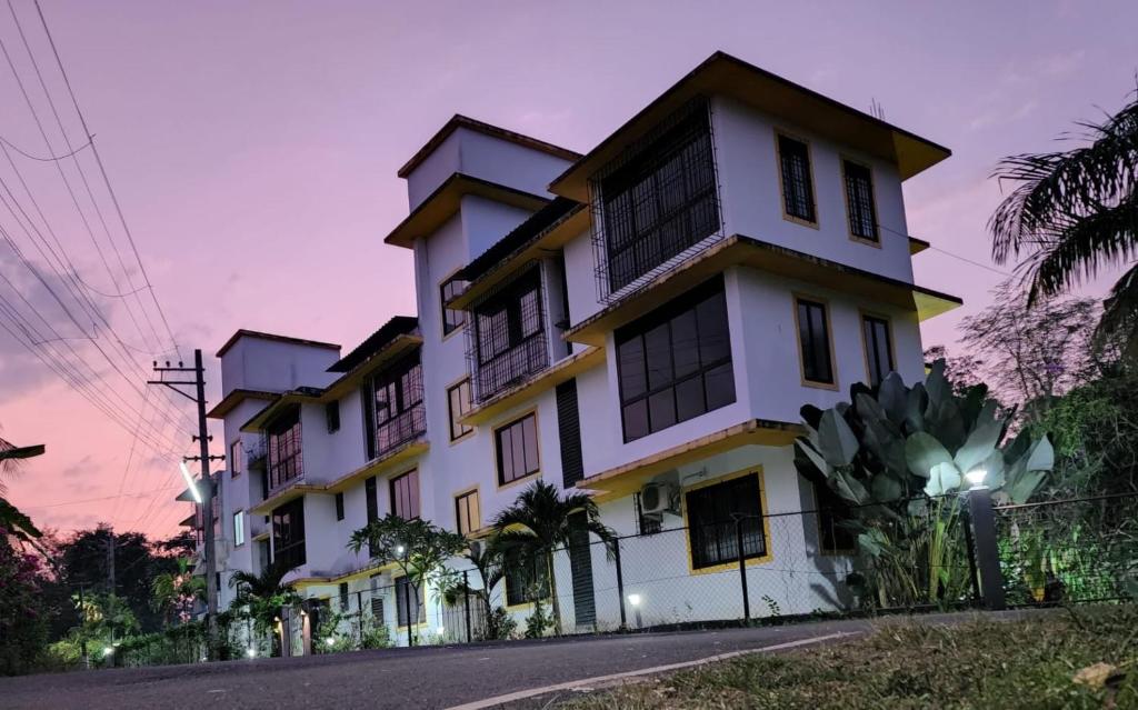 a large white building with a sunset in the background at 002 MŸKA at Dsouza Heritage, Moira in Mapusa