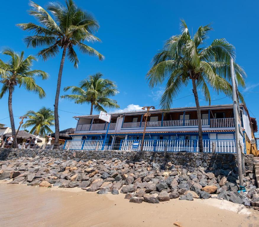 ein Gebäude am Strand mit Palmen in der Unterkunft Amendoeira Praia Hotel in Morro de São Paulo