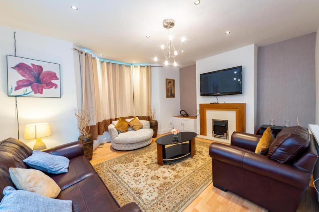 a living room with a leather couch and a fireplace at Chestnut Heritage,- Large & Cheerful 5 bedroom house with free parking in Liverpool