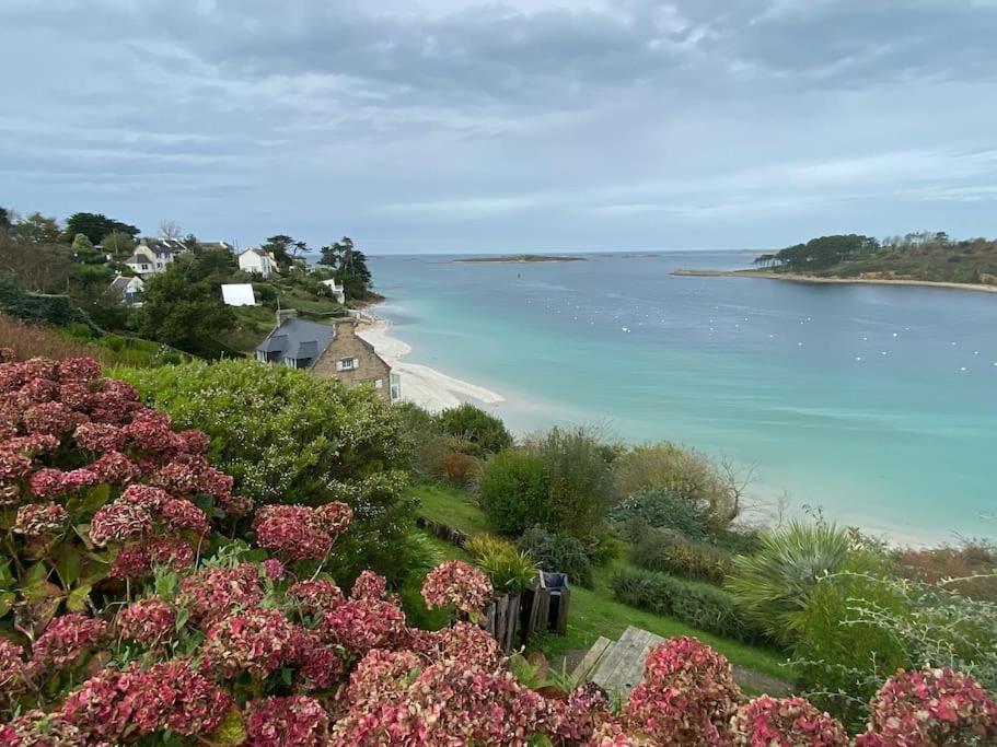 Blick auf den Strand mit einem Haus und Blumen in der Unterkunft Maison neuve, chaleureuse, vue sur L'Aber Benoït in Saint-Pabu